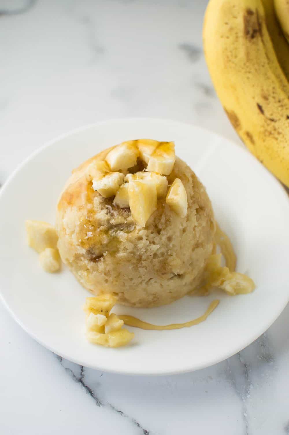 Honey Peanut Butter Banana Mug Cake on Plate with pieces of banana and honey drizzle on the top