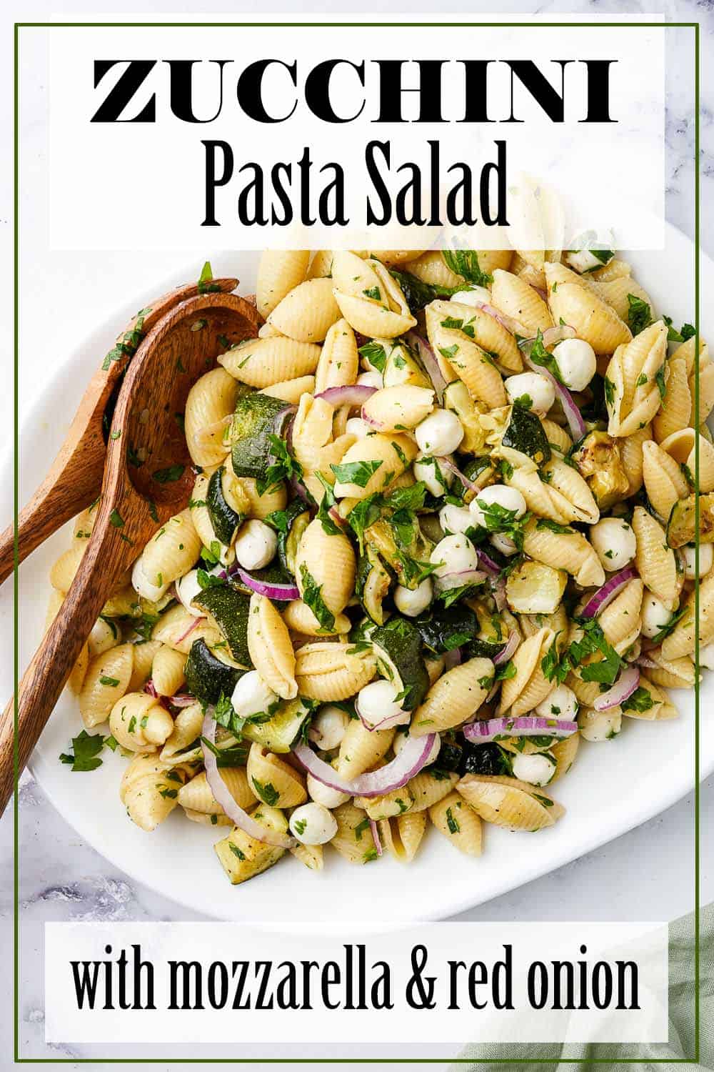 Zucchini Pasta Salad on White Platter with 2 Wooden Spoons