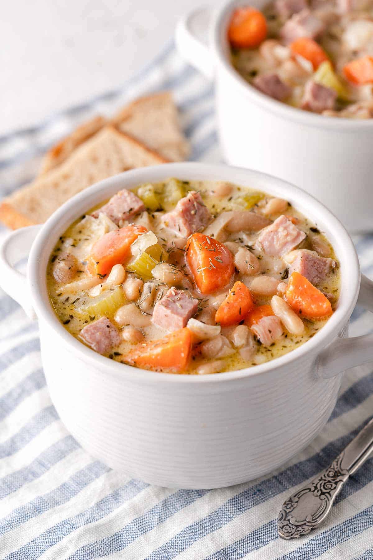 ham and white bean chowder in two bowls with bread on the side