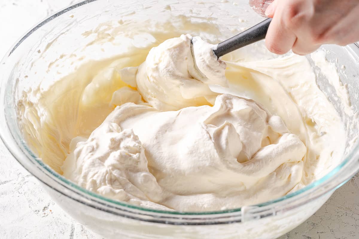 spatula folding whipped cream into cream cheese mixture