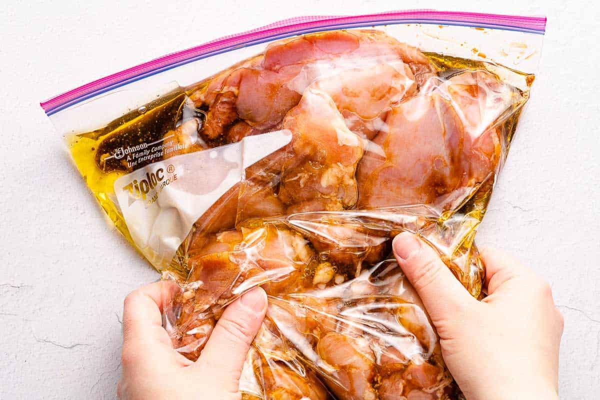chicken and marinade in bag being massaged with hands