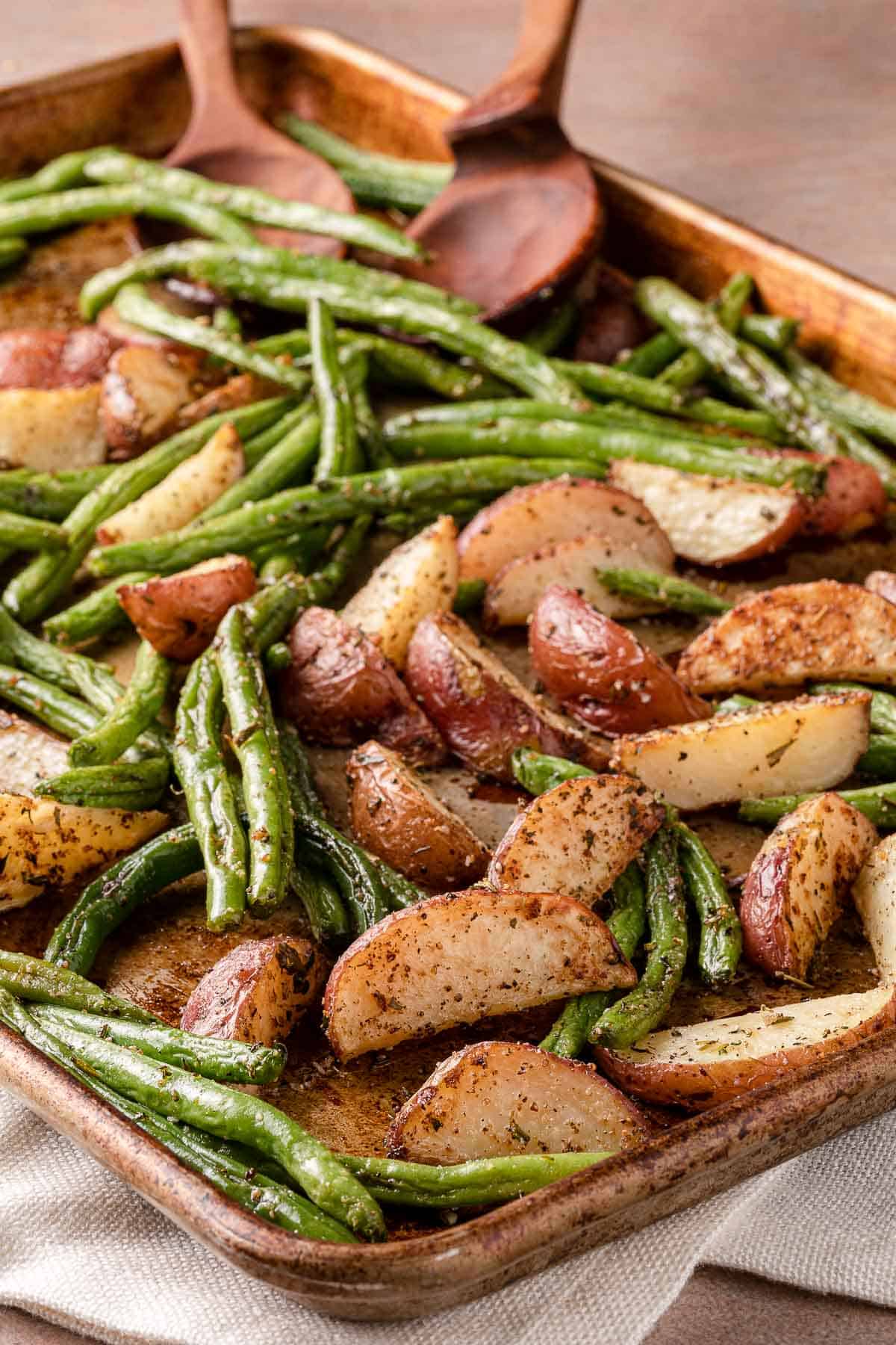 potatoes and green beans on sheet pan with wooden spoon