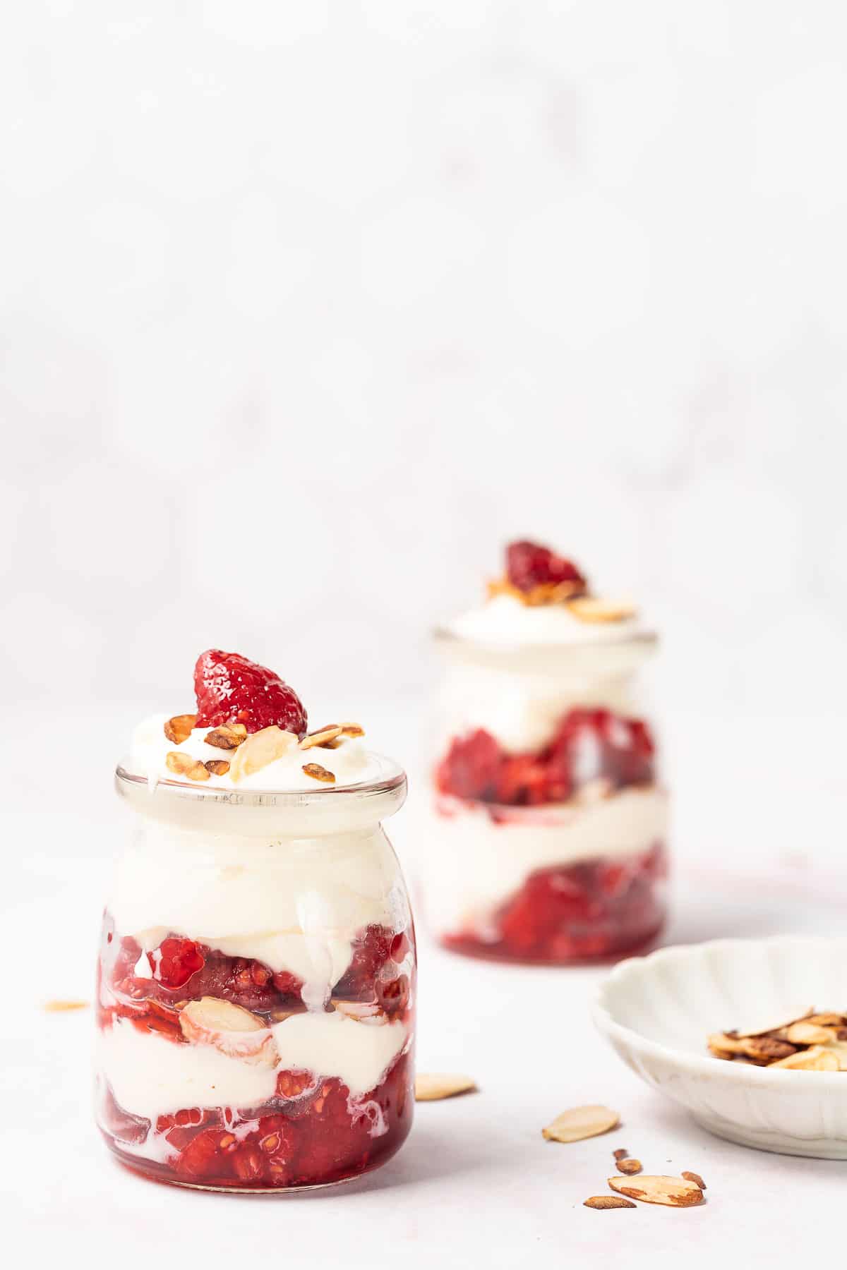 two raspberry ricotta parfaits with almonds on the side