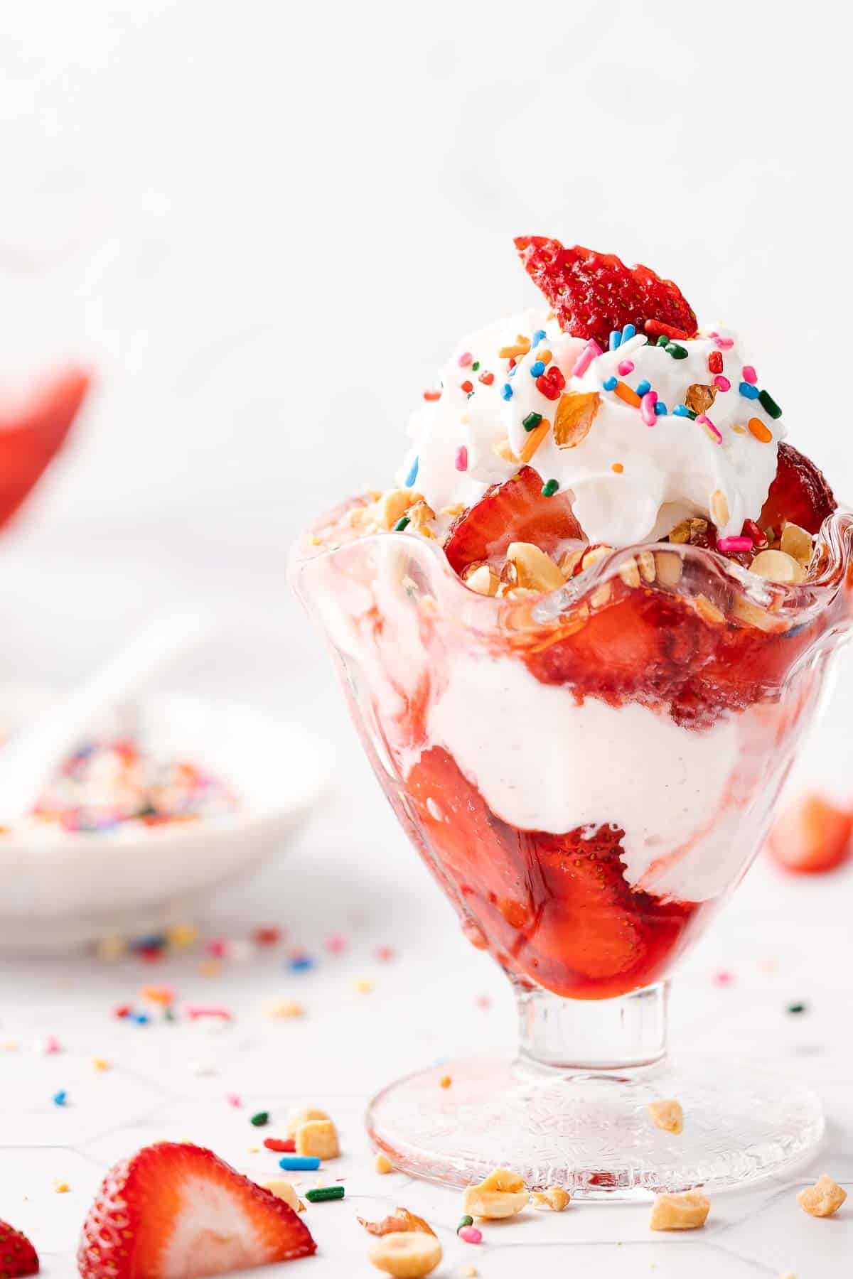 strawberry sundae with dish of sprinkles on the side