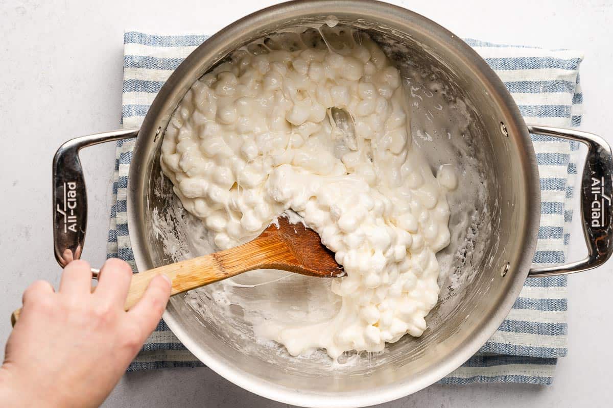 wooden spoon stirring melting marshmallows in large pot
