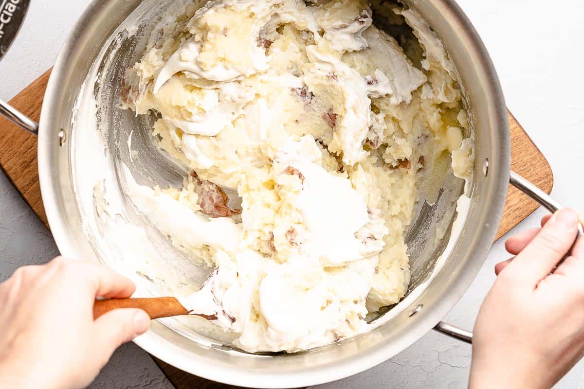 sour cream being stirred into mashed potatoes