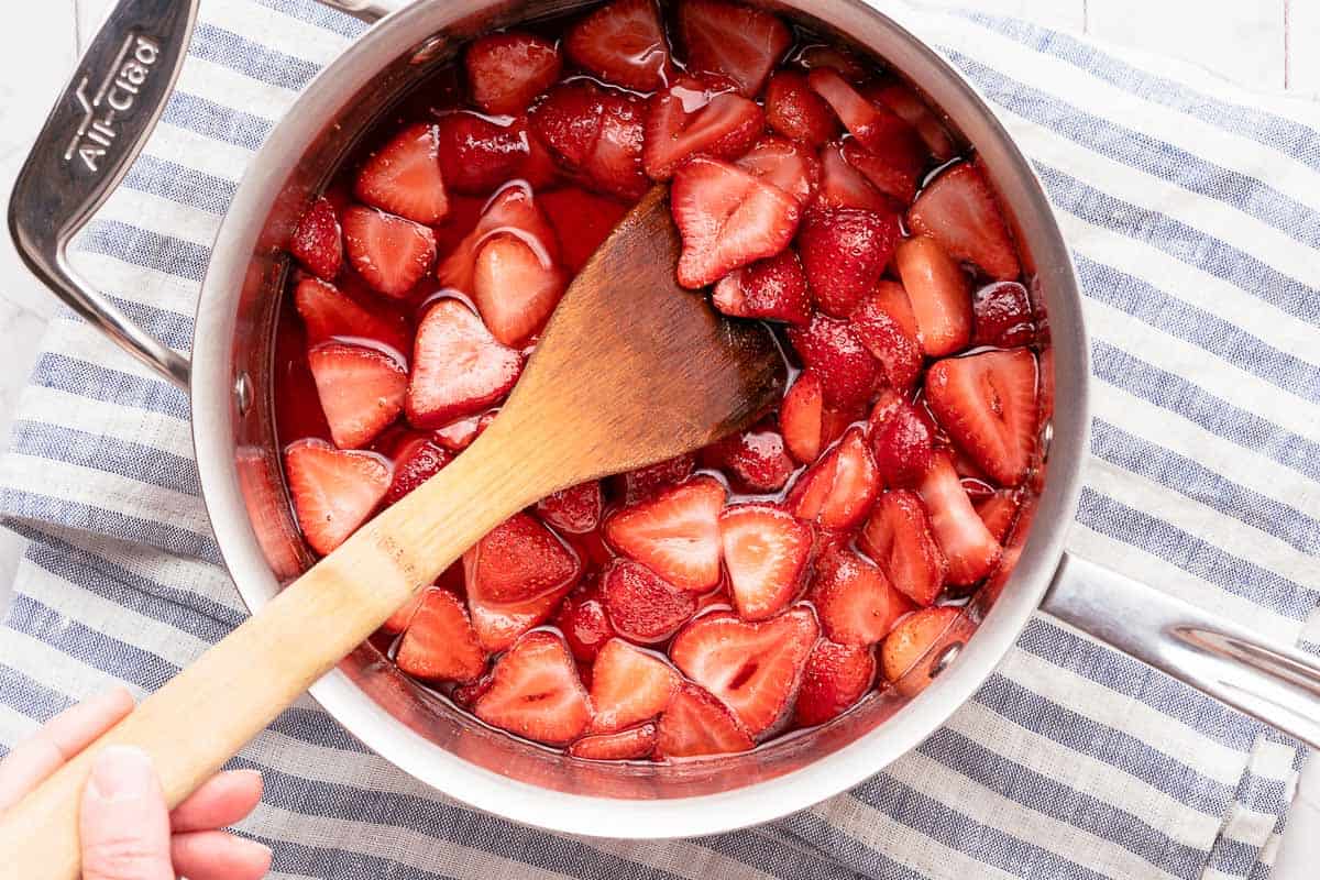 strawberry sundae sauce in pan with wooden spoon