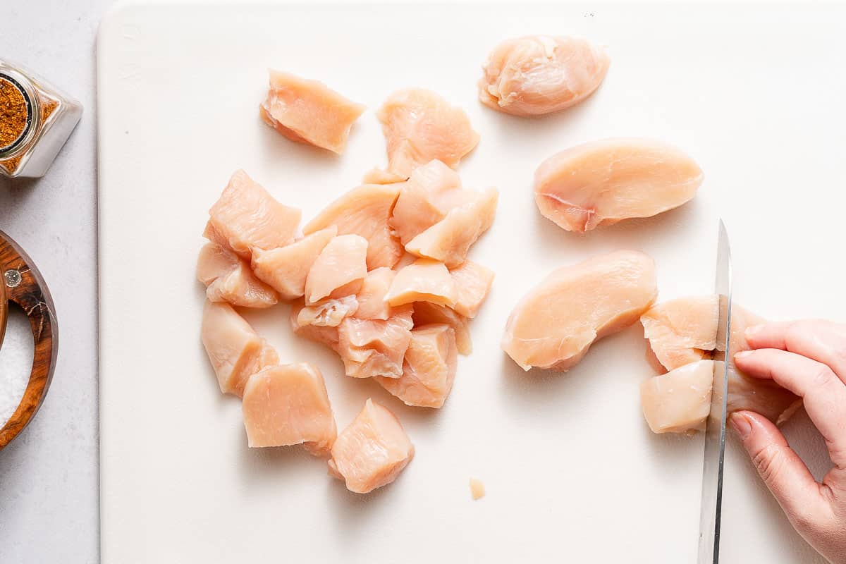 chicken breasts being cut into chunks 