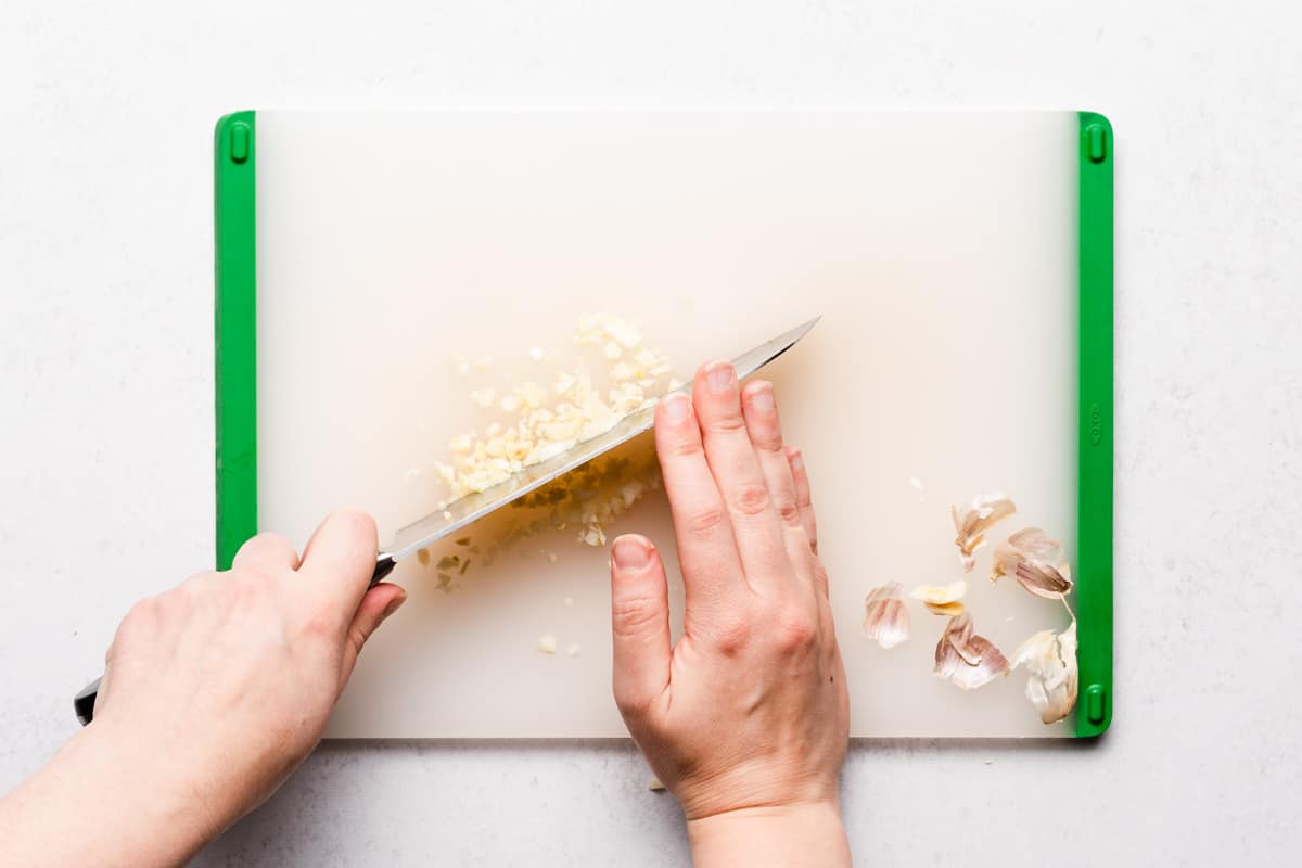 knife chopping garlic on cutting board