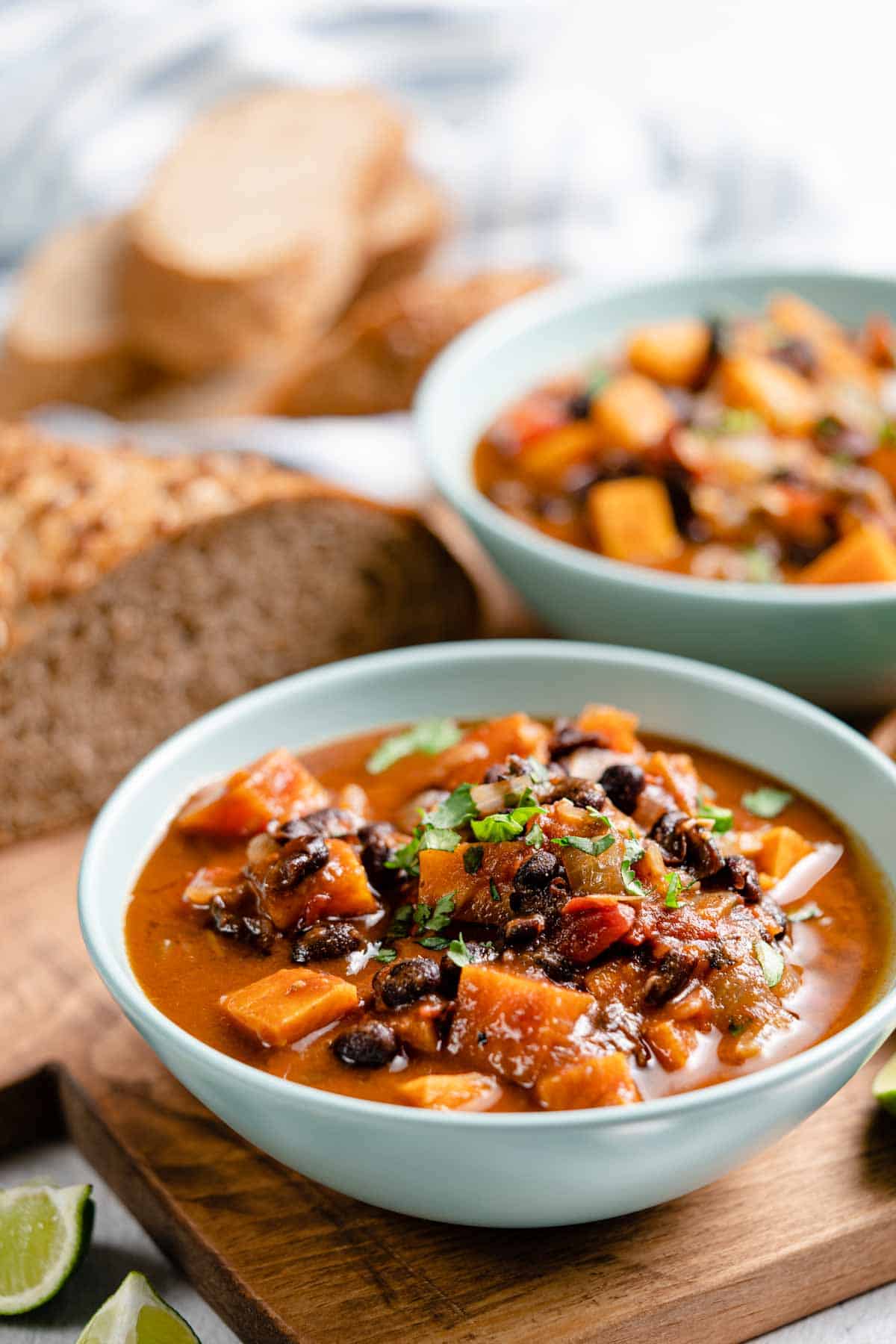 sweet potato black bean soup in two bowls with bread on the side