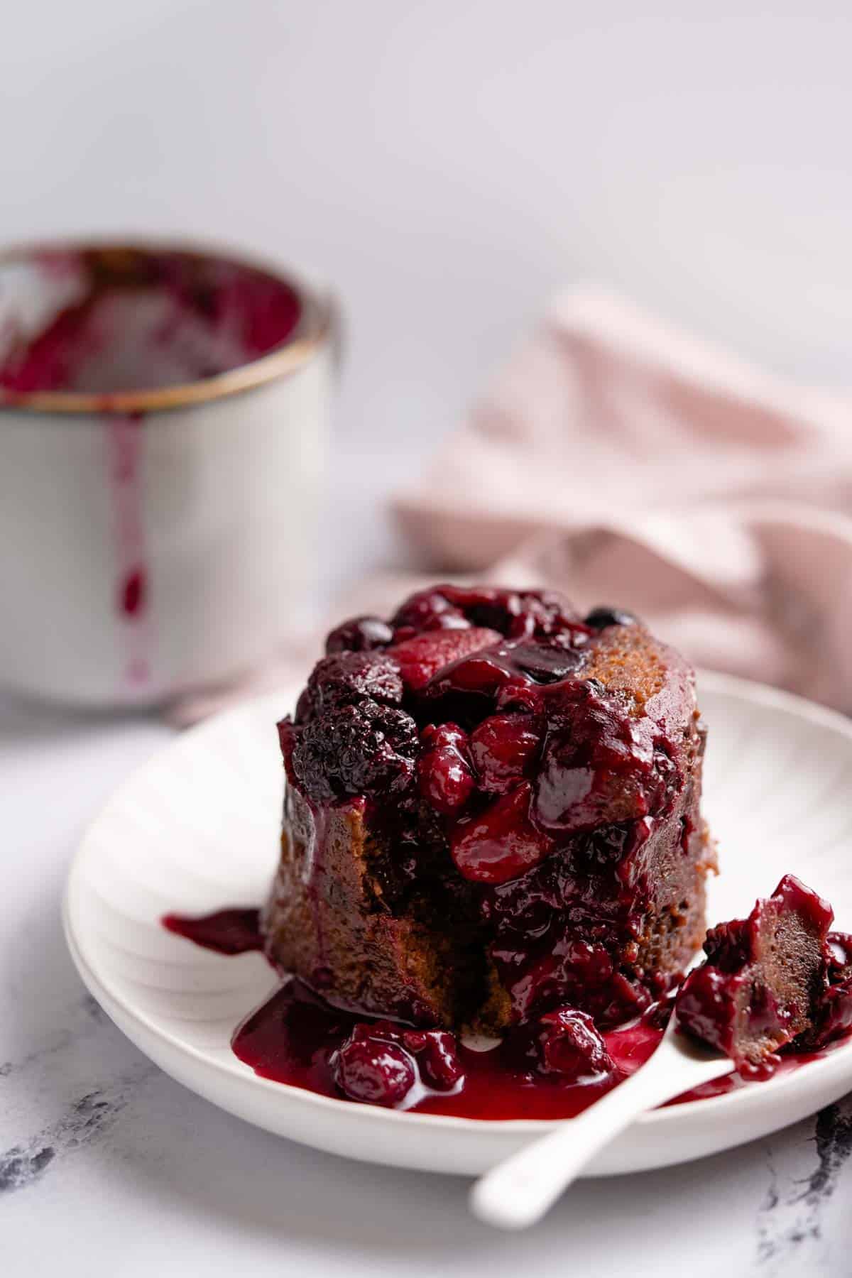 chocolate berry mug cake on plate with mug and napkin in background