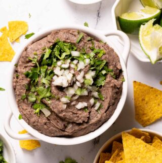 bean dip in bowl with chips and lime on the side