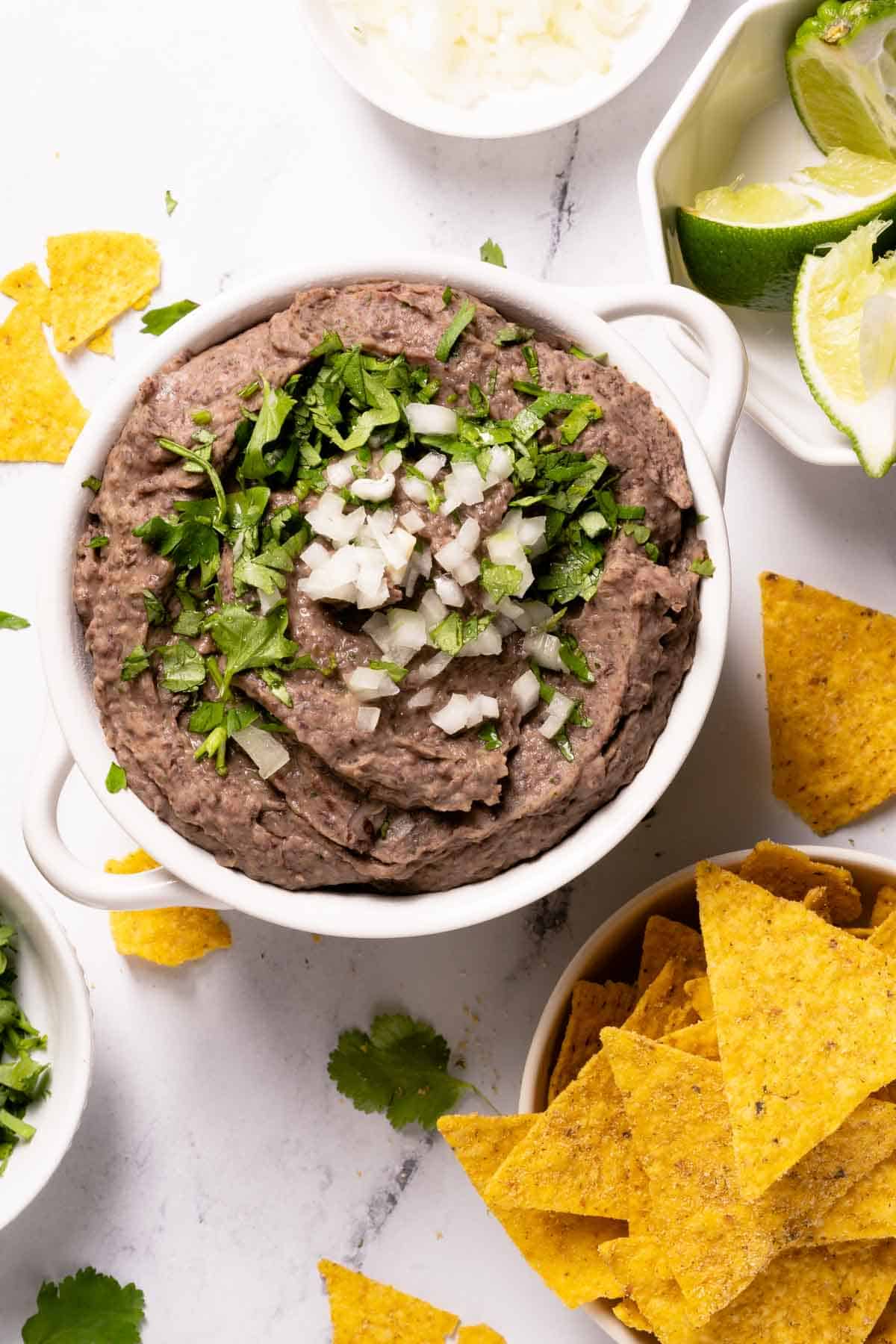 bean dip topped with cilantro and onion with chips on the side