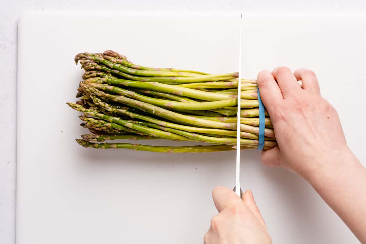 knife cutting ends off of bundle of asparagus