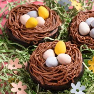 donuts with frosting in the shape of a nest with centers filled with pastel chocolate eggs