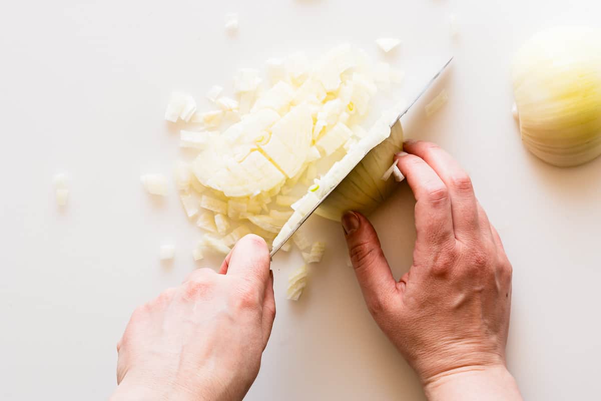 onion being chopped on white cutting board