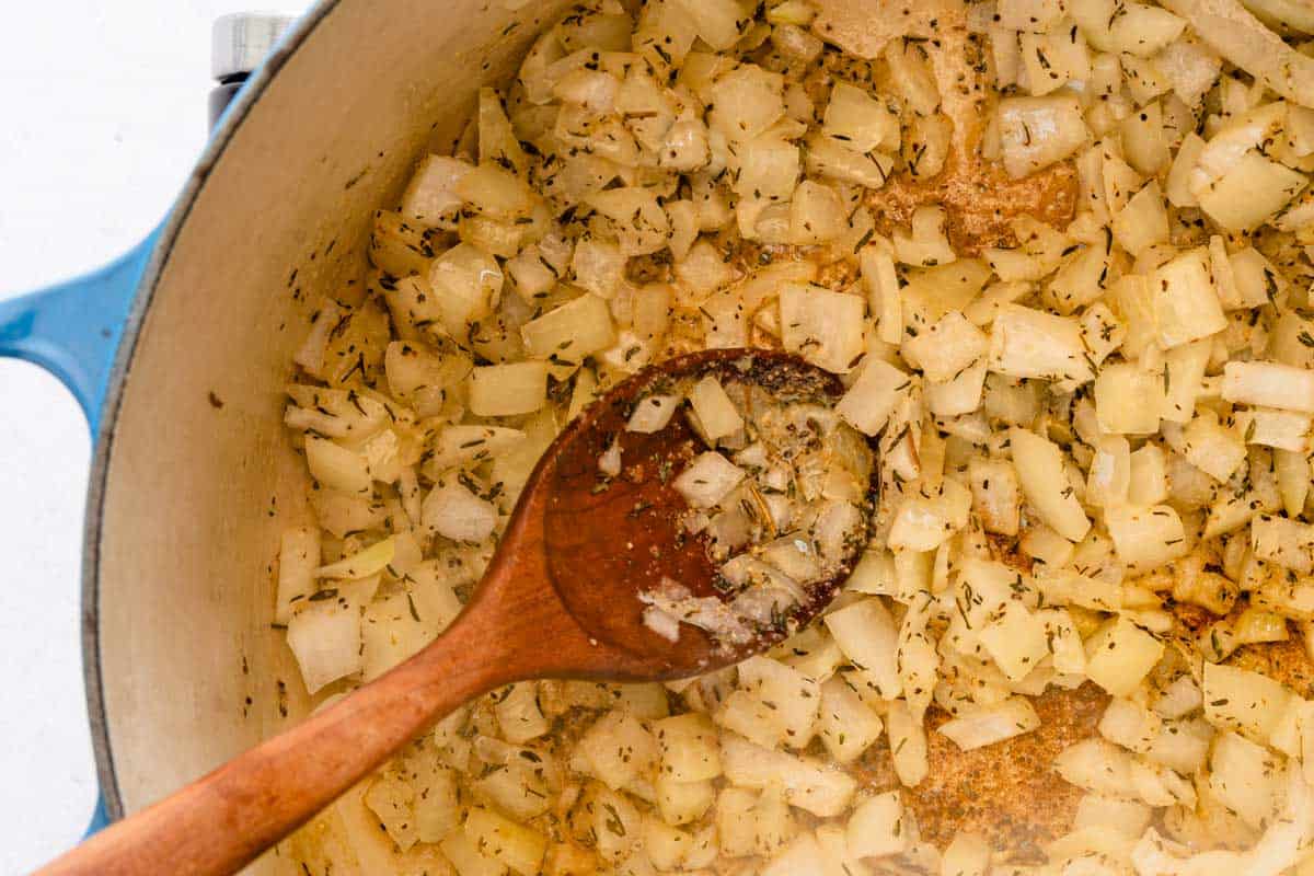 cooked onion and spices in pot with wooden spoon
