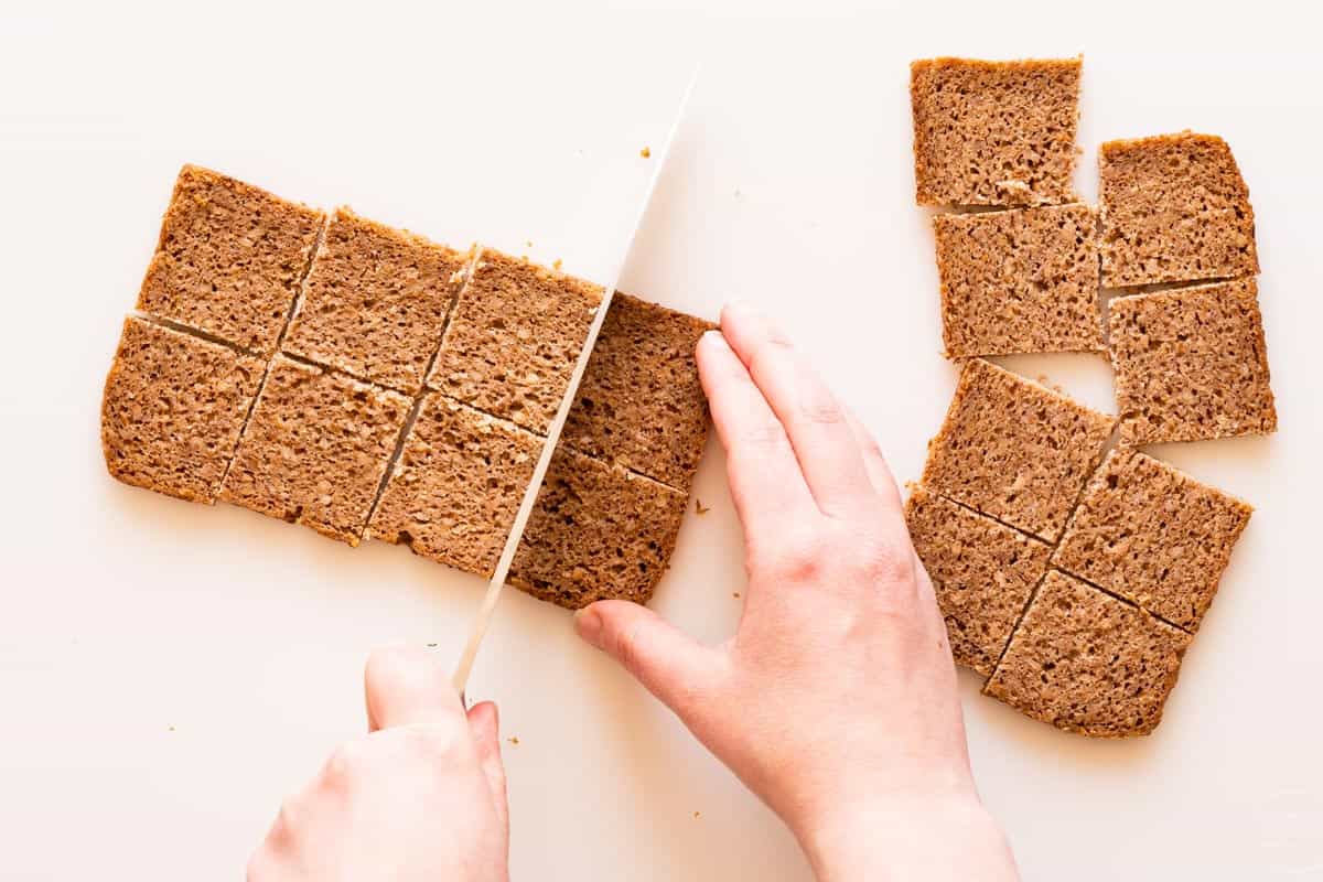 slice of bread being cut into small squares with more squares of bread on the side