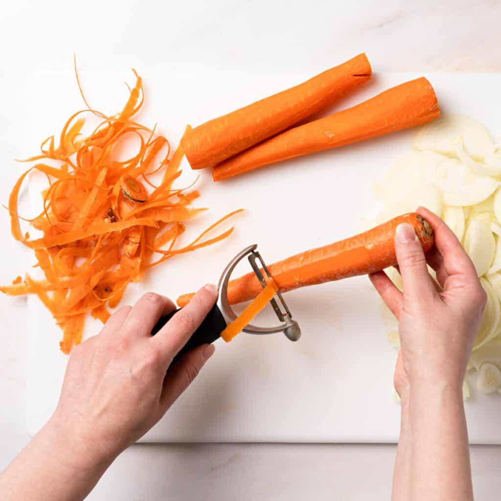 carrots being peeled with vegetable peeler
