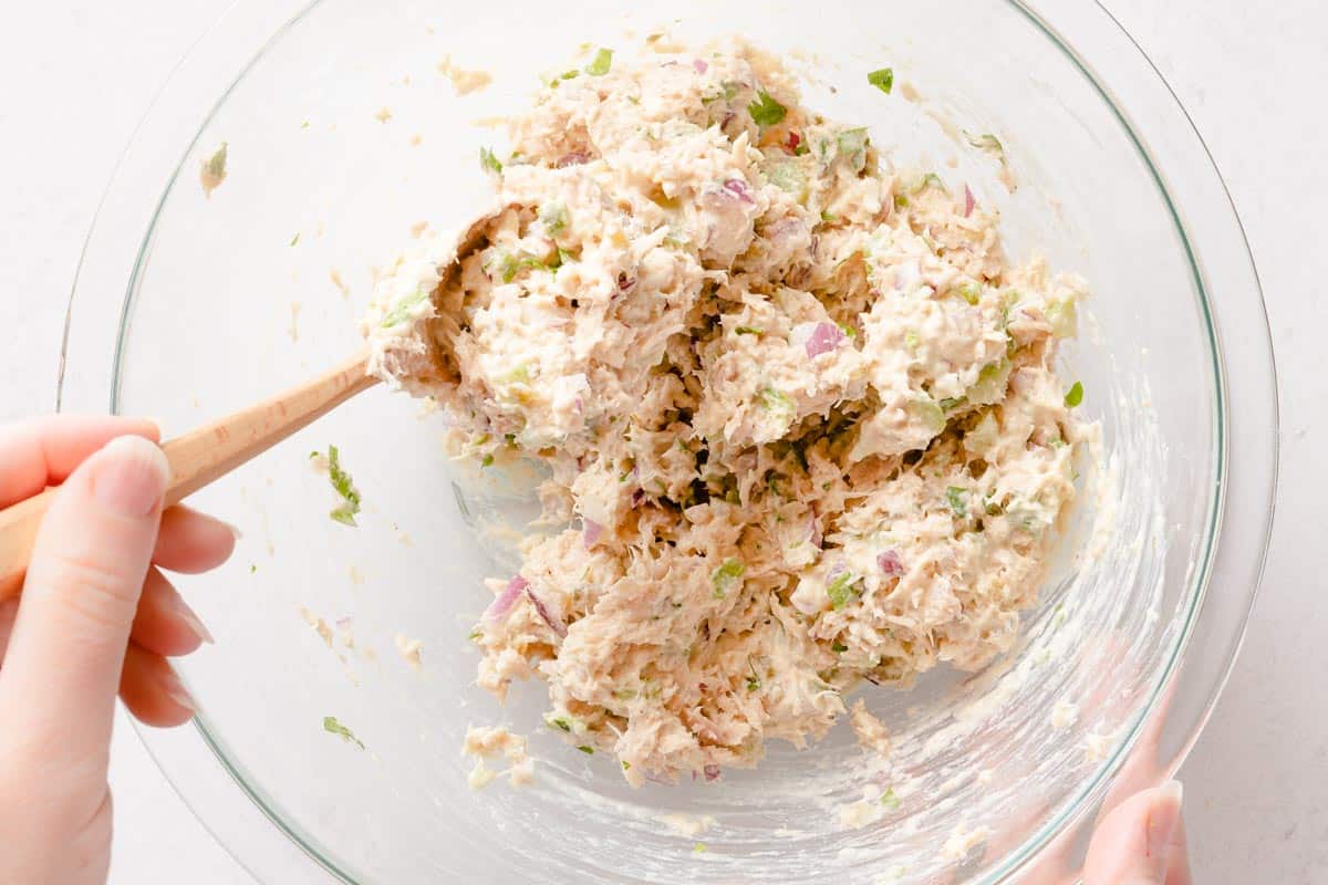 Greek yogurt tuna salad being mixed with wooden spoon