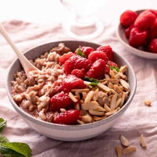 bowl of oatmeal topped with raspberries and almonds