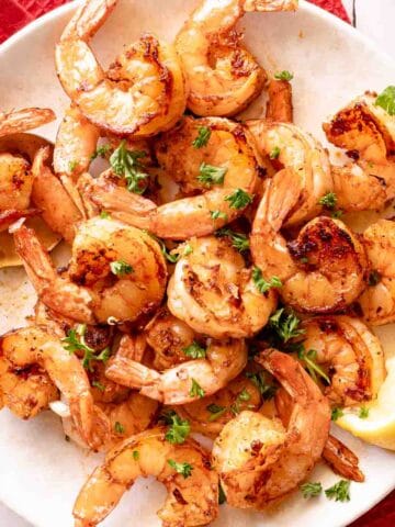 seared shrimp on plate with spoon and lemon on the side.