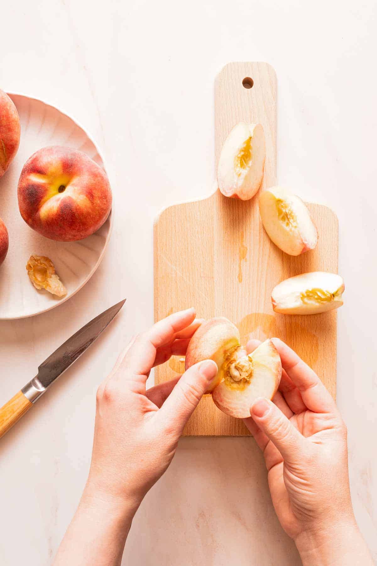 hand pulling apart peach into wedges.