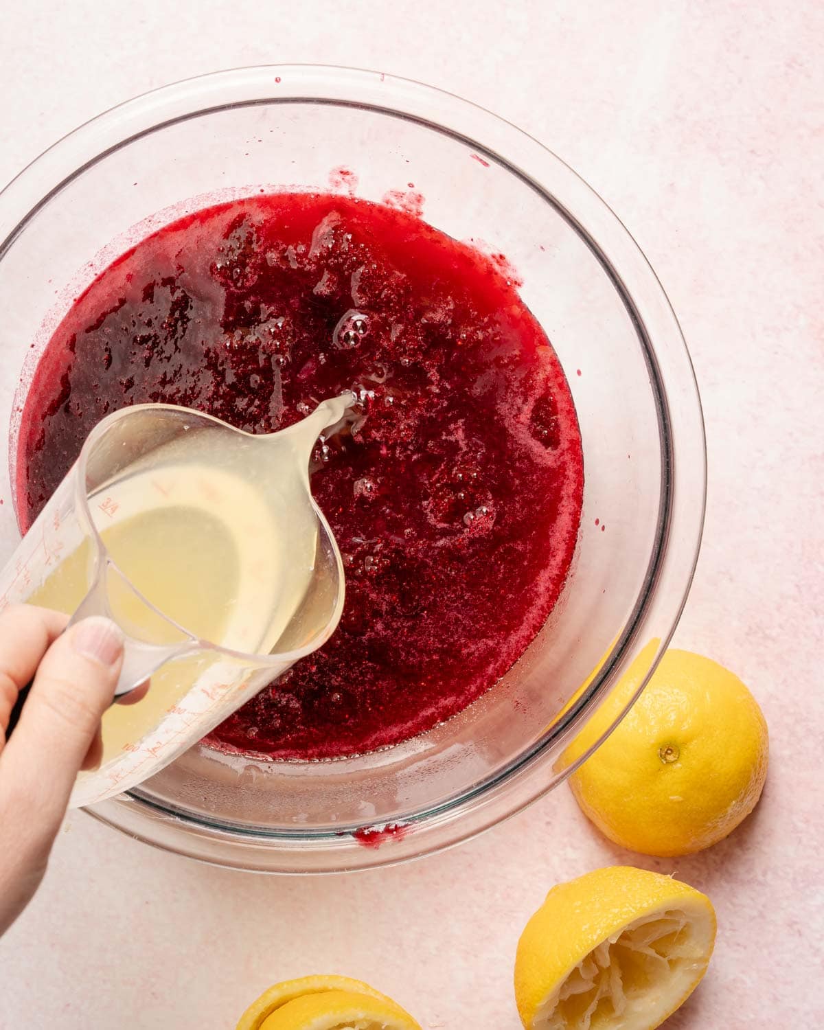 lemon juice being poured into a bowl with berry juice inside.