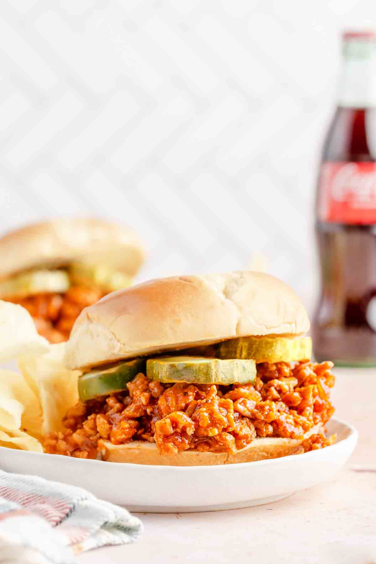sloppy joe made with ground chicken garnished with pickle slices on white plates.