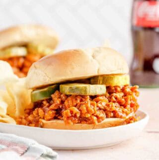 chicken sloppy joe with pickles on white plate.