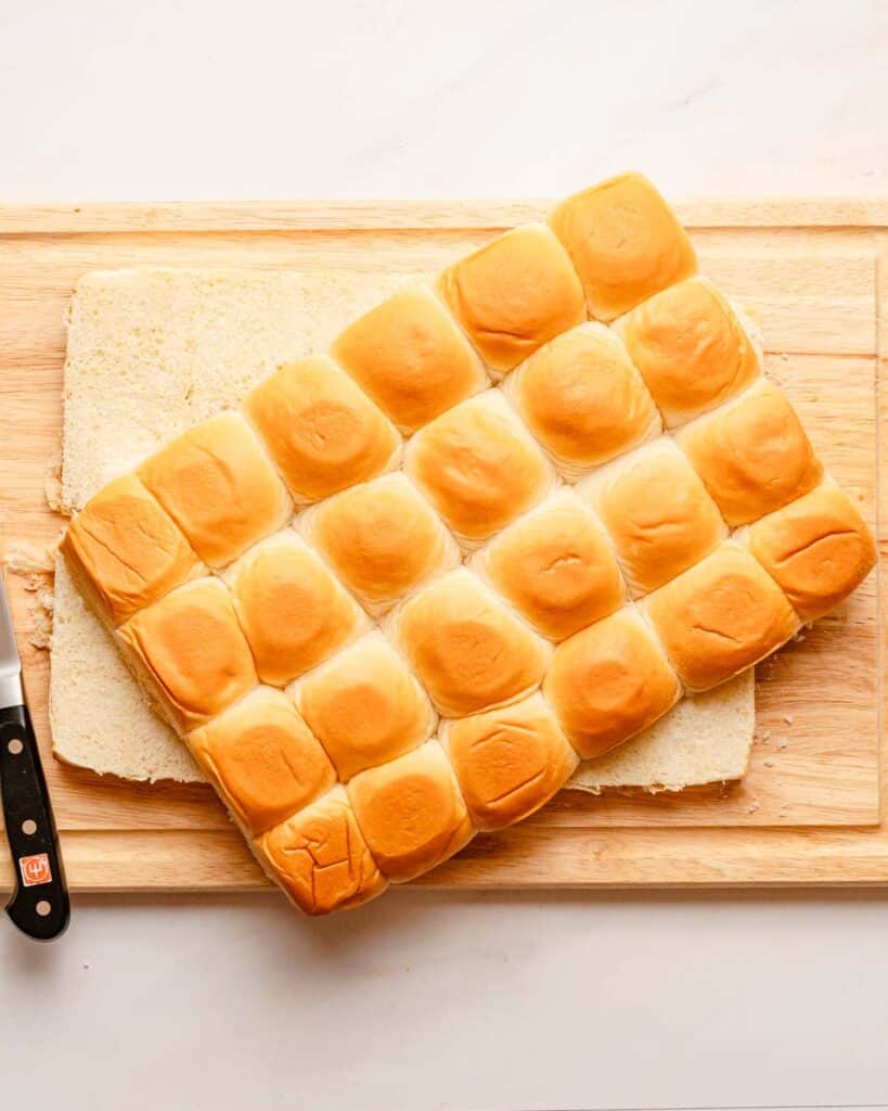 mini rolls sliced in half horizontally on a cutting board.