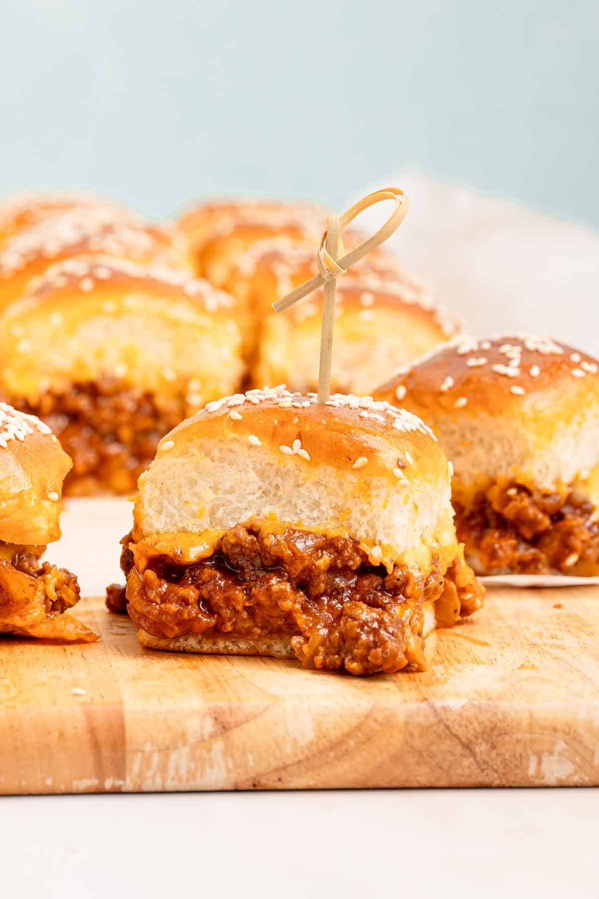 sloppy joe slider with toothpick on wooden cutting board.