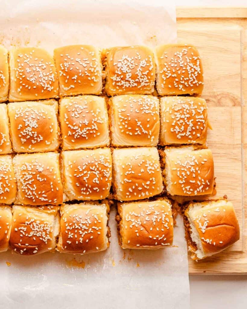 sloppy joe sliders cut apart on a wooden cutting board.