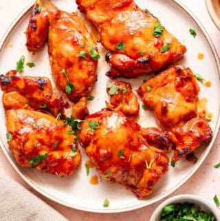 bbq chicken thighs on plate with parsley on the side.
