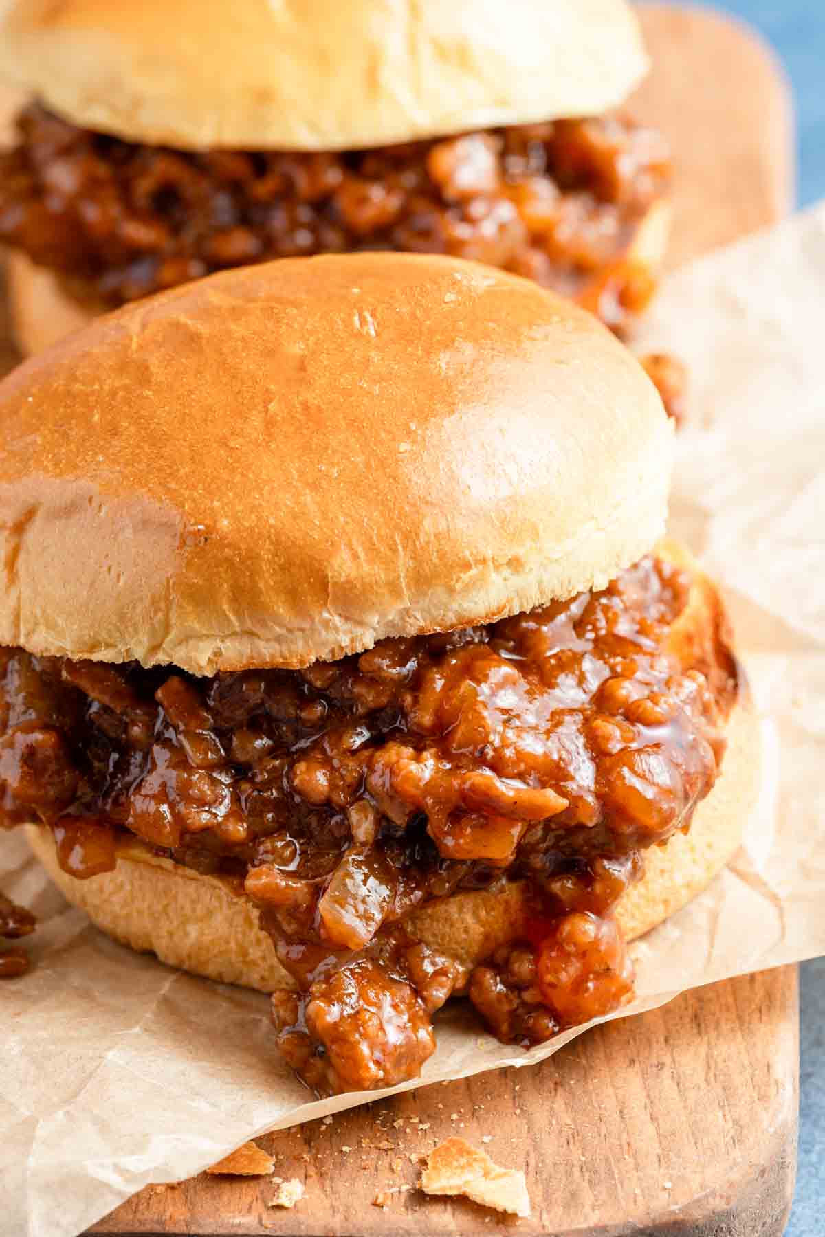 two sloppy Joes on parchment paper.