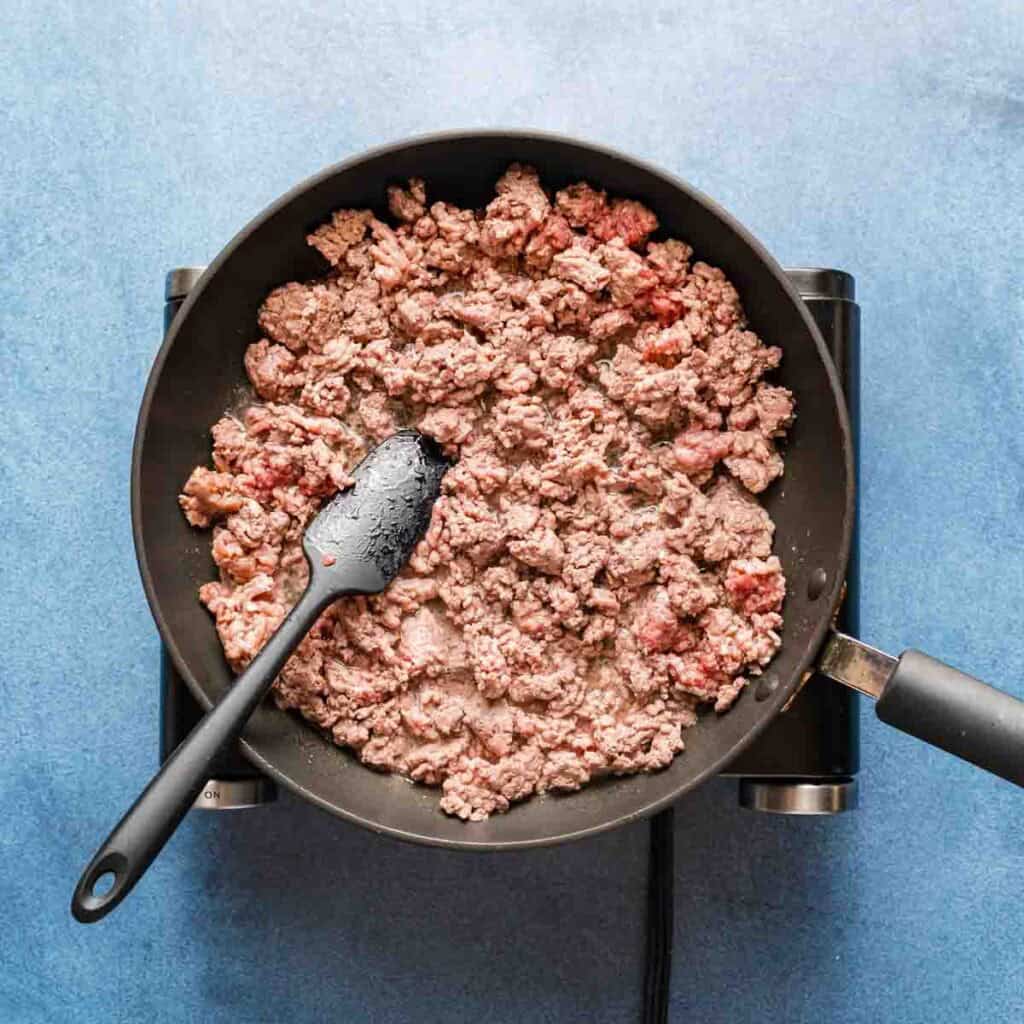 ground beef in skillet with spatula.