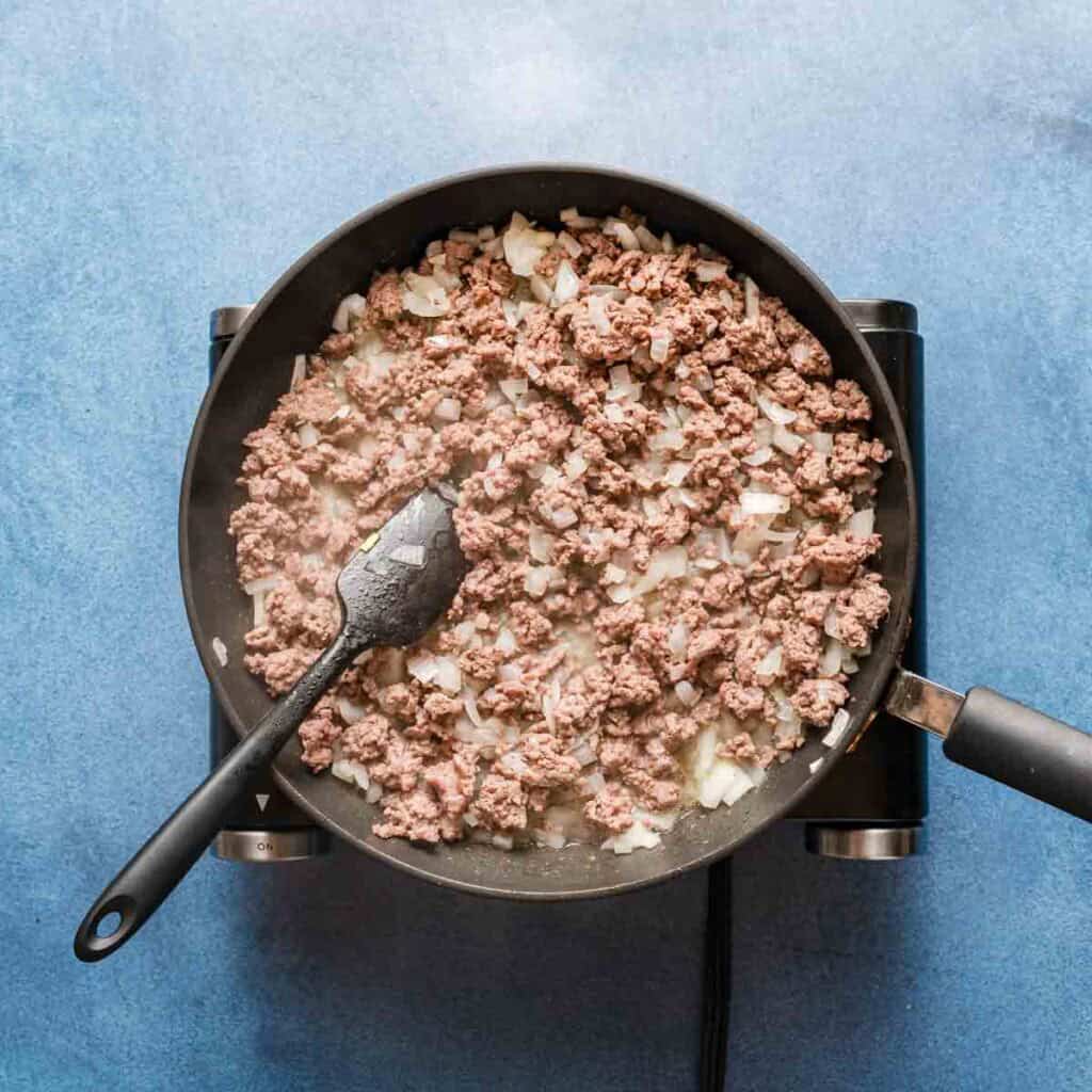 ground beef and diced onion cooked in a skillet.