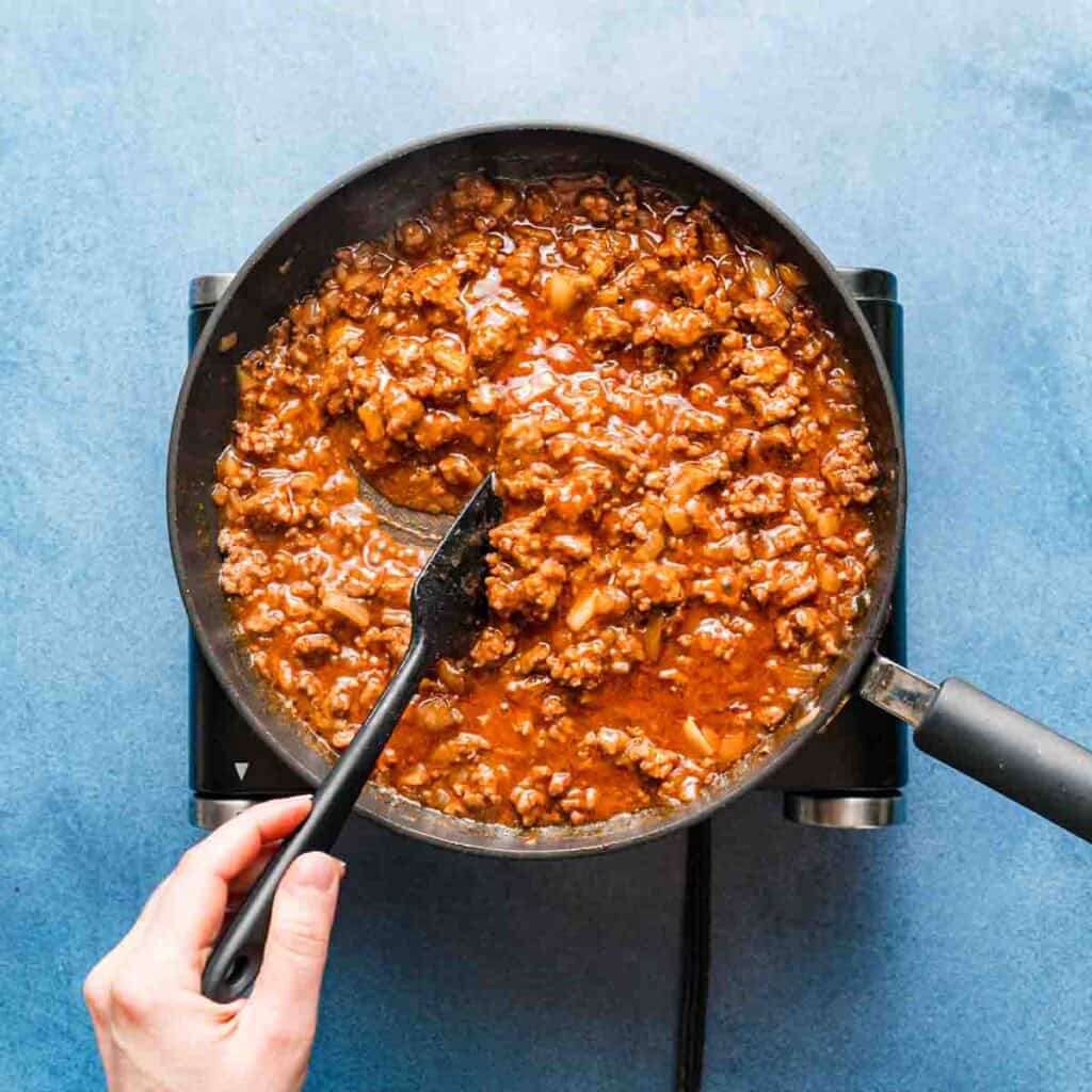 cooked sloppy Joe mix in a skillet being stirred with a spatula.