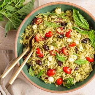 bowl of orzo pesto pasta salad with basil garnish.
