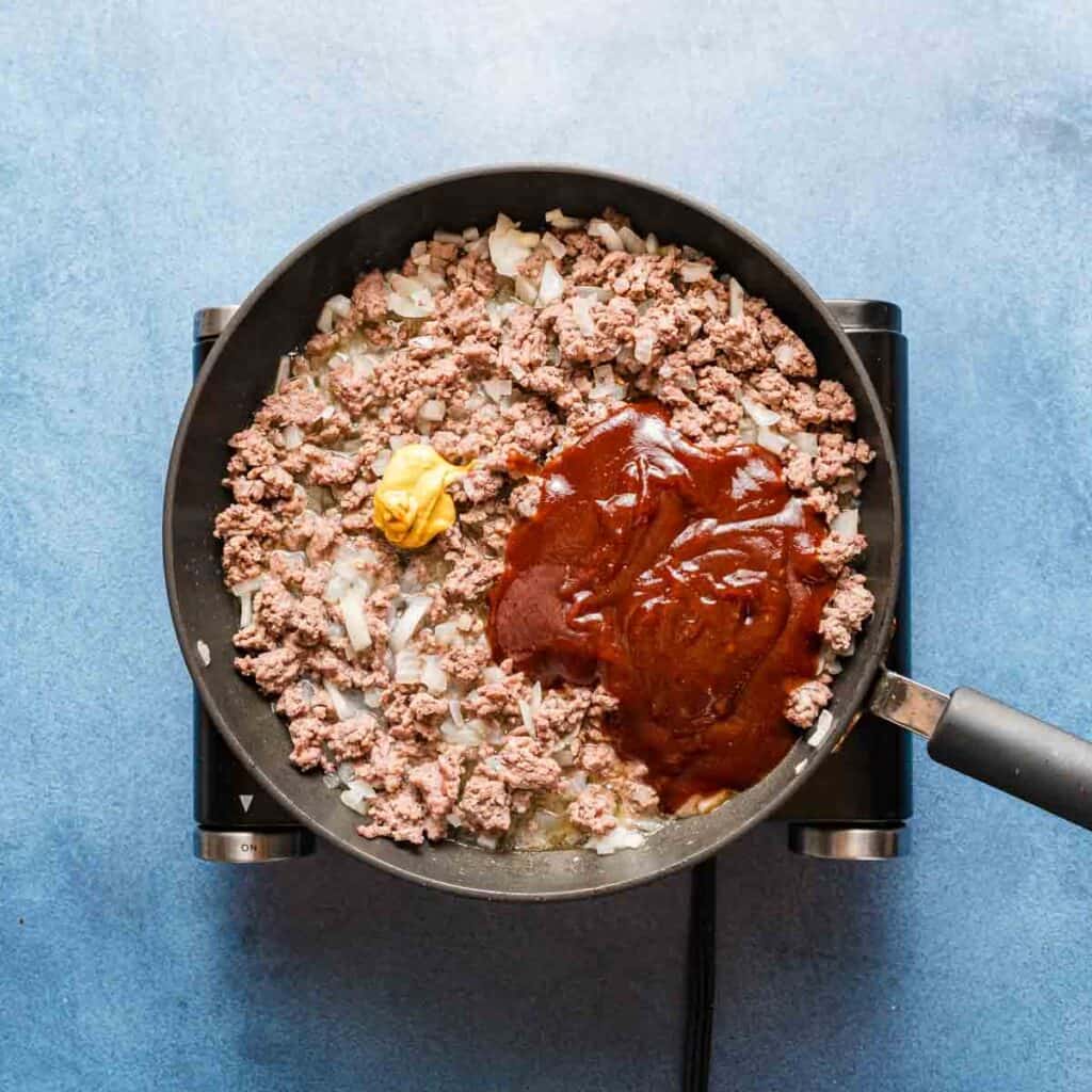cooked beef in pan with bbq sauce and mustard on the top.