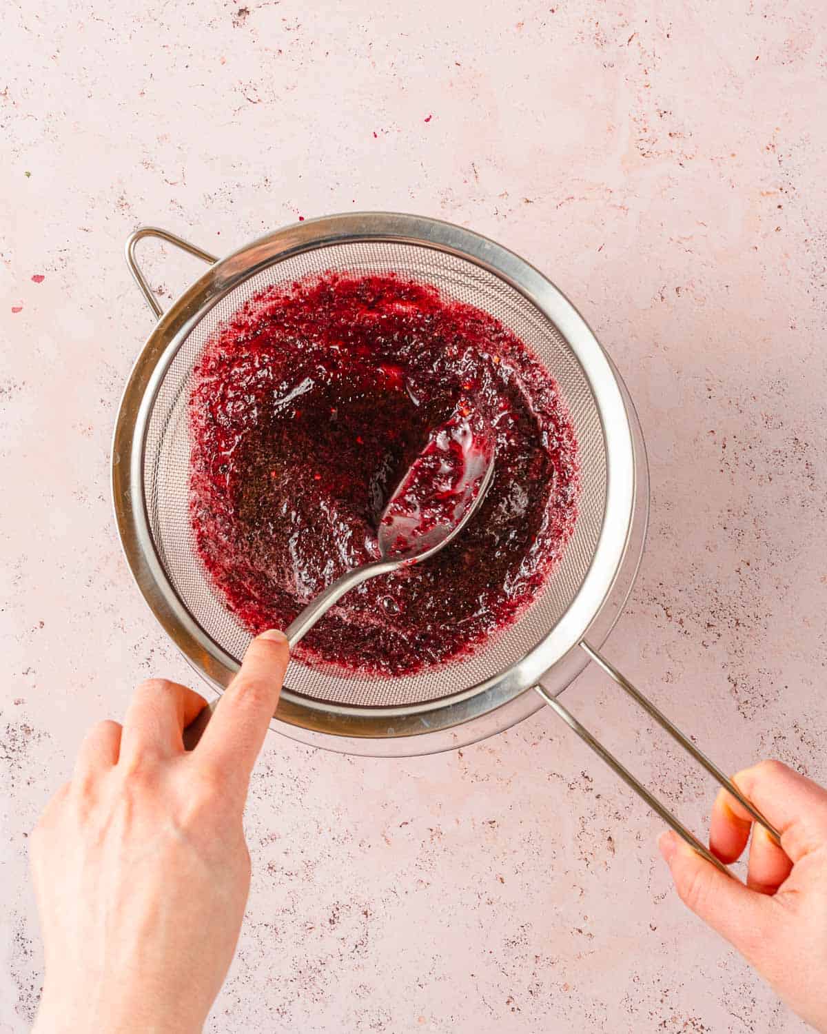 cherry pulp being drained in a fine mesh strainer.