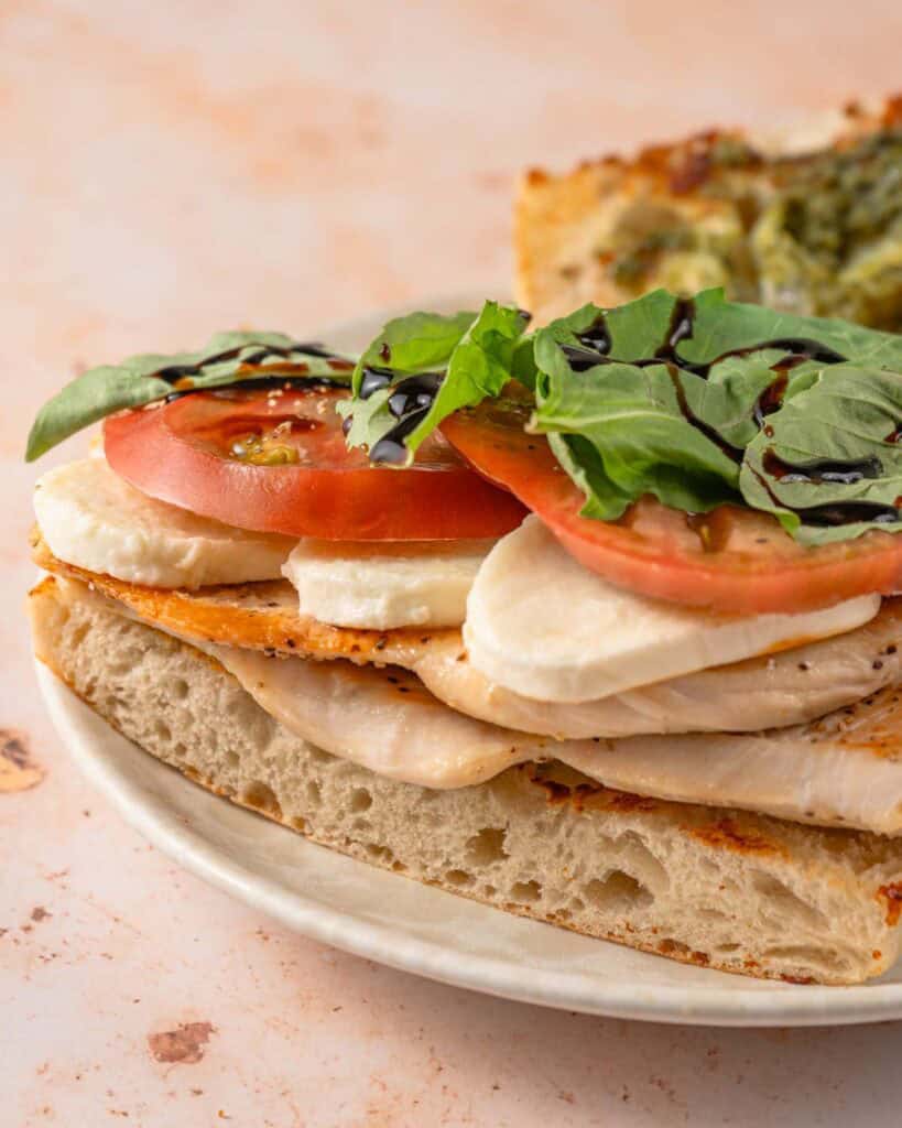 sandwich with chicken breast tomato fresh mozzarella and basil on a plate.