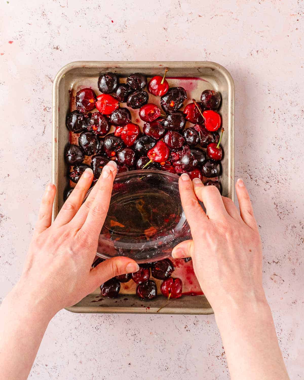 cherries in tray being squished with glass.