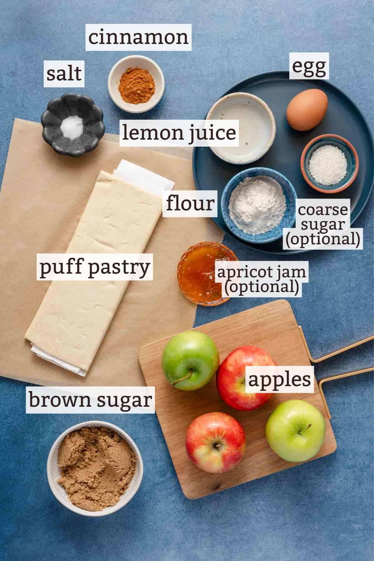 ingredients for apple galette on blue background with text labels.