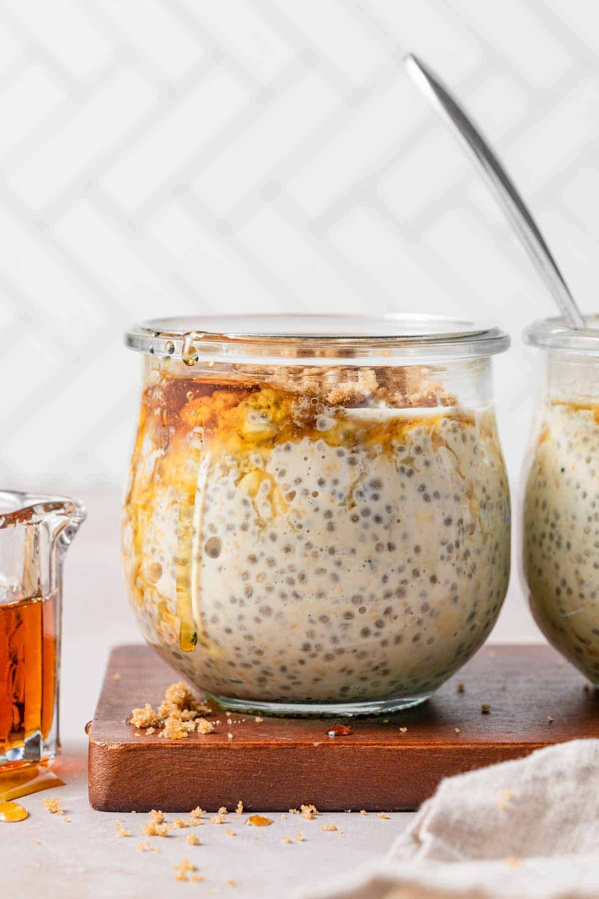 jar of overnight oats topped with maple syrup and brown sugar.