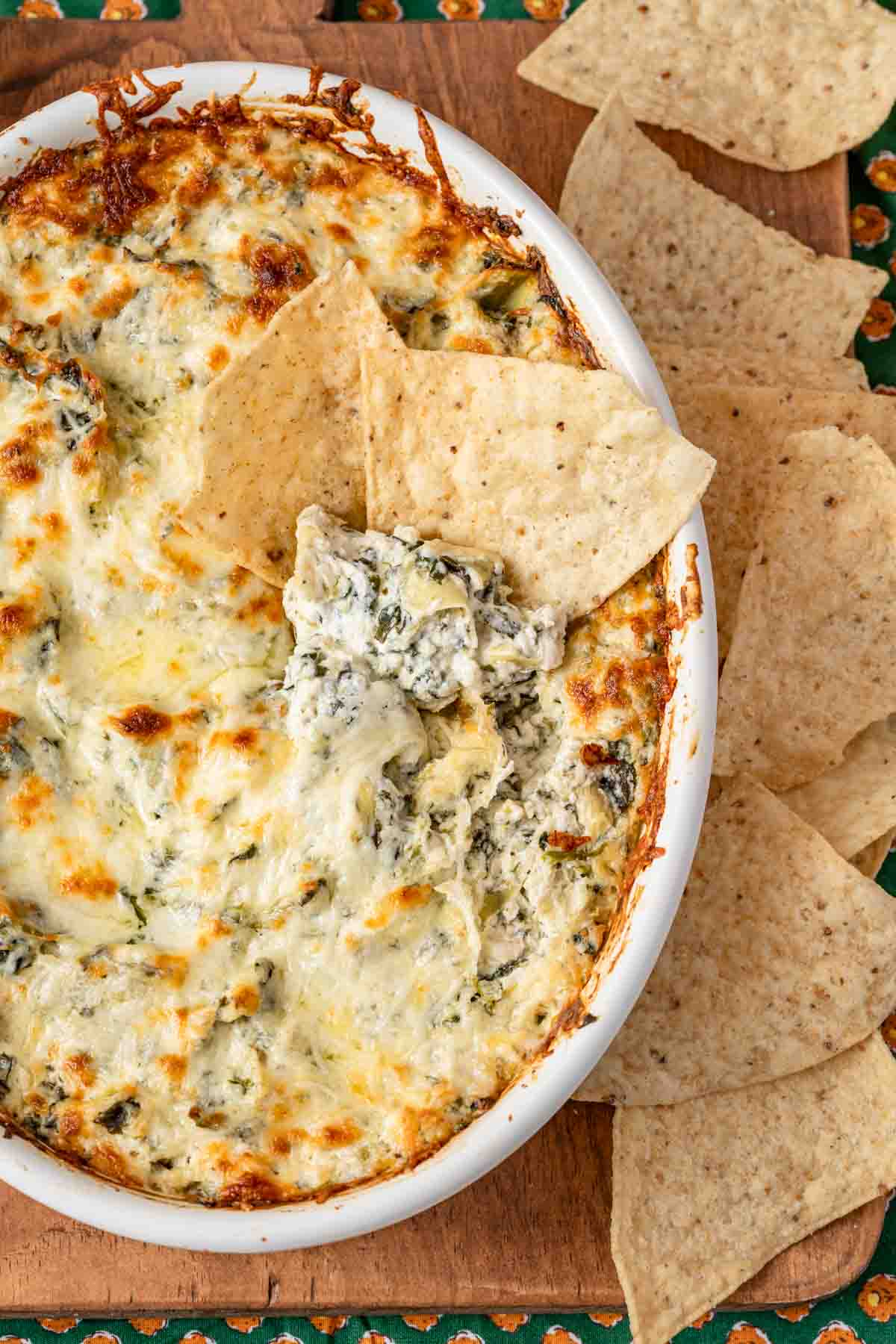 baked dip with cheesy top in oval casserole dish with tortilla chips on the side.