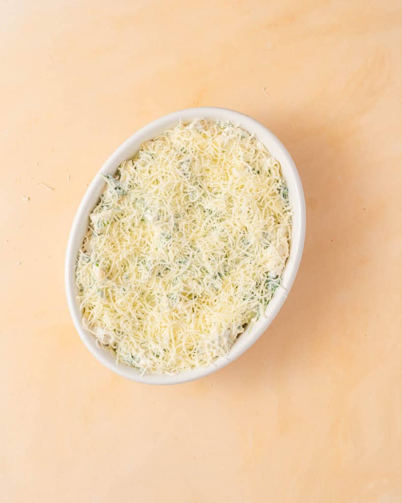 dip in oval casserole dish topped with shredded cheese.