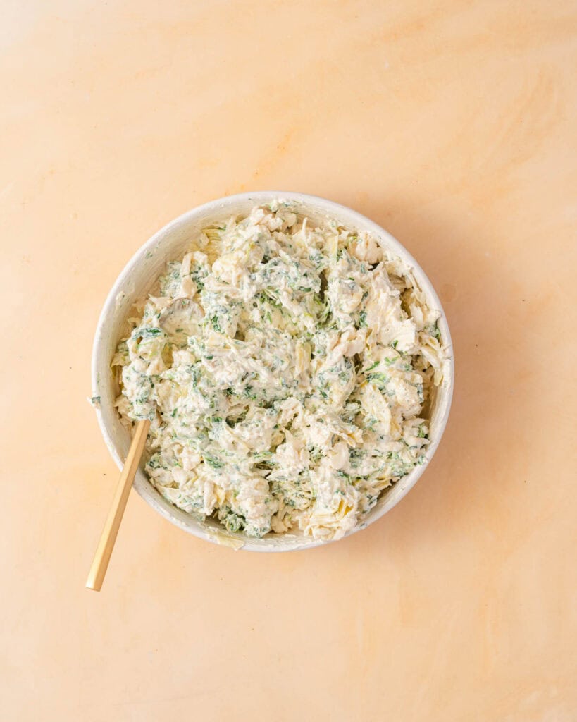 artichoke heart spinach and cheeses blended in a bowl.