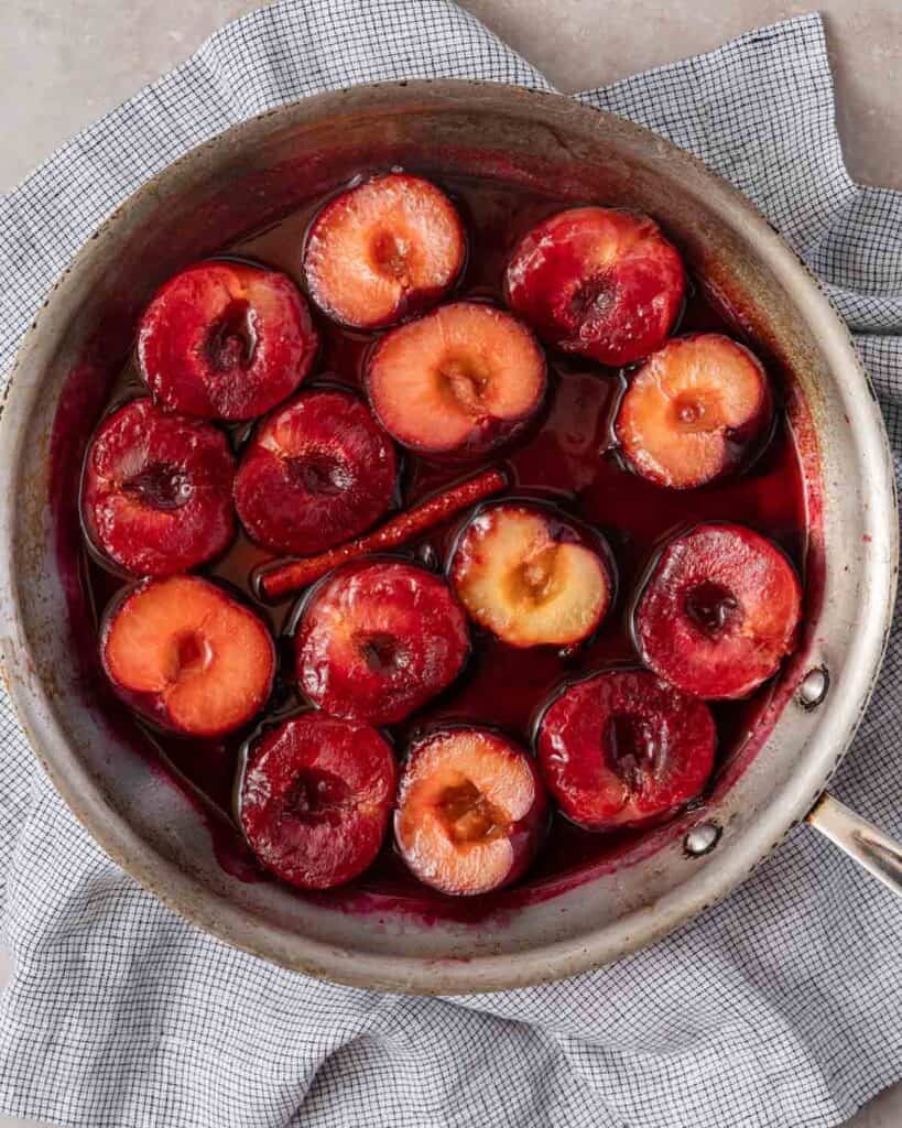 cooked plum halves in liquid in skillet.