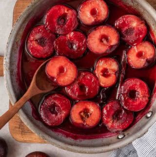 cooked plum halves in liquid in skillet.